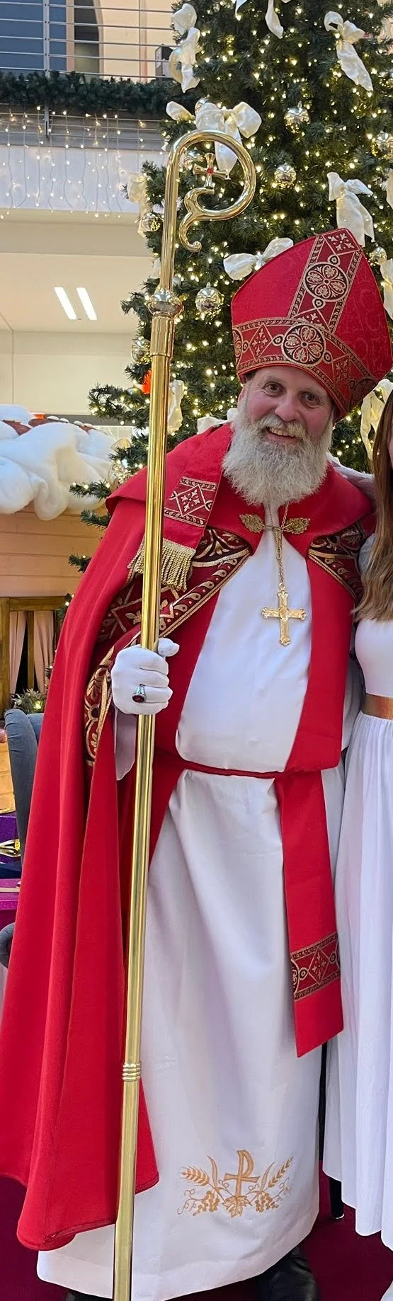 Der Nikolaus mit Mitra und Bischofsstab vor einem Weihnachtsbaum